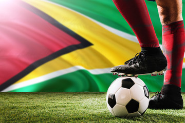 Close up legs of Guyana football team player in red socks, shoes on soccer ball at the free kick or penalty spot playing on grass.