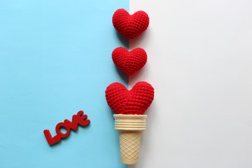 Red handmade crochet heart in waffle cup on yellow and pink background for valentines day