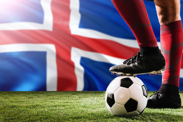 Close up legs of Iceland football team player in red socks, shoes on soccer ball at the free kick...