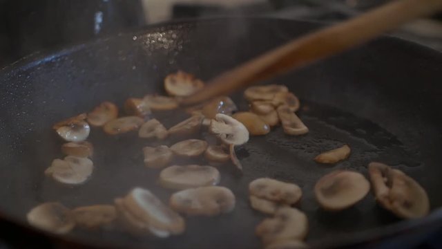 Mushroom meal being prepared with the mushrooms sizzling in the pan and steam coming out from the heat. Cooking concept.