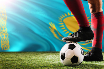 Close up legs of Kazakhstan football team player in red socks, shoes on soccer ball at the free...