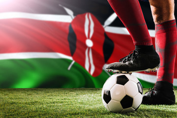 Close up legs of Kenya football team player in red socks, shoes on soccer ball at the free kick or...