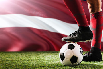 Close up legs of Latvia football team player in red socks, shoes on soccer ball at the free kick or...