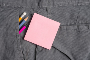 Writing equipment and pink note paper inside pocket of man work trousers