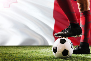 Close up legs of Malta football team player in red socks, shoes on soccer ball at the free kick or...