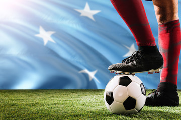 Close up legs of Micronesia football team player in red socks, shoes on soccer ball at the free kick or penalty spot playing on grass.