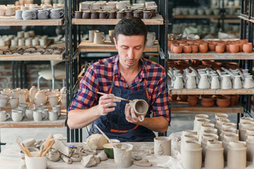Talanted caucasian man making decoration for cup.