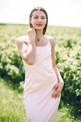 Naklejka na ściany i meble Beautiful girl in pink dress walking in the field of currants