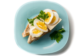 Fried Egg on Toast for Breakfast. Fried egg with bread and parsley on white plate on black, top view, copy space.