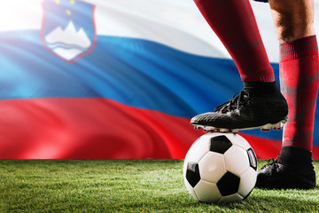 Close up legs of Slovenia football team player in red socks, shoes on soccer ball at the free kick...