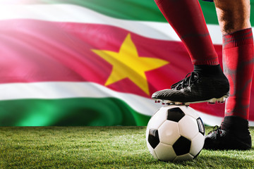 Close up legs of Suriname football team player in red socks, shoes on soccer ball at the free kick...