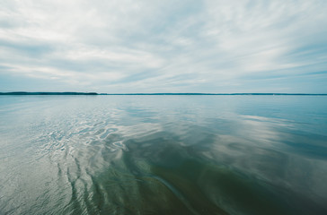 Big clean lake and white clouds in the blue sky.