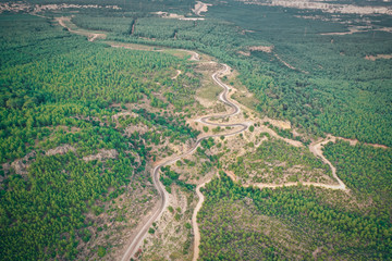 Top down view of road bending through trees at sunset