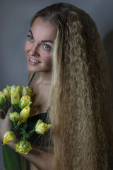 Young beautiful girl with a bouquet of yellow tulips