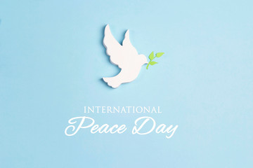 World Peace Day greeting card. Dove of peace with olive branch on a blue background.