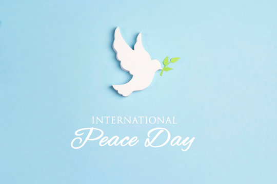 World Peace Day greeting card. Dove of peace with olive branch on a blue background.
