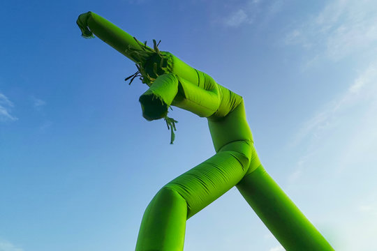 Inflatable dancing, flailing arms tube guy, against blue sky and clouds