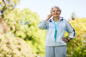 fitness, sport and healthy lifestyle concept - senior woman with earphones at summer park