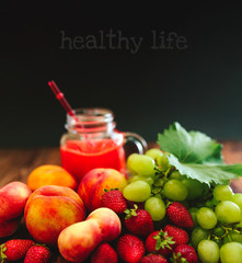 Fresh fruits and freshly squeezed juice on wooden background.