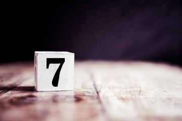 Number 7 isolated on dark background- 3D number seven isolated on vintage wooden table - obrazy, fototapety, plakaty