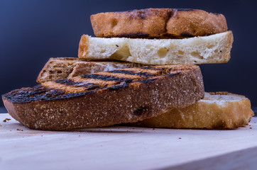 Grilled crispy slice of bread on a wooden board. On navy background.