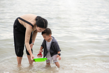 Mom is teaching her son. To learn and explore the sand on the sea beach