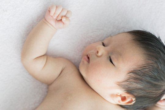 Asian newborn baby sleeping on the bed in living room