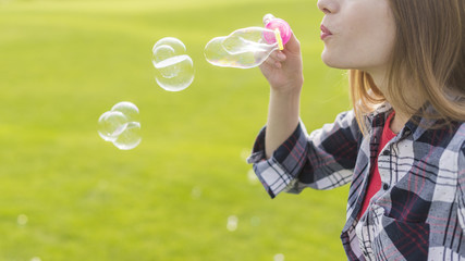 Side view blonde girl making soap bubbles