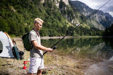 Fisherman fishing in nature at lake while camping outdoor