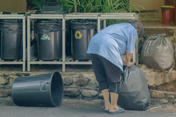Female worker sort the garbage and packed in black bags for transportation convenience.