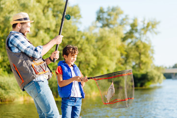 Man feeling happy after catching fish with his beaming son