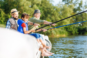 Boy feeling happy while fishing with father and grandfather