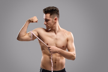 Fototapeta premium Strong man measuring arm muscles