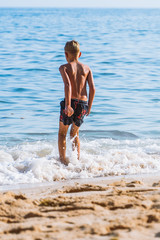 Fototapeta na wymiar toddler jumping in sea waves at the beach. kids fun at vacation time. travel with children