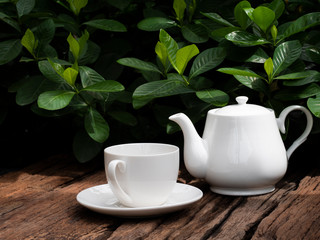 Ceramic white tea cup and jug on wooden background.