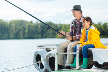 Bearded mature man fishing sitting near grandson