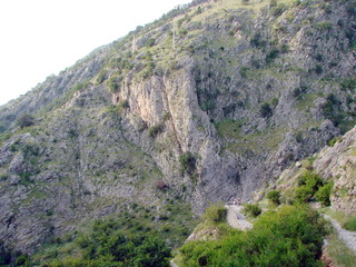 Natural picture of inaccessible rocks covered with poor vegetation under the rays of the setting sun.