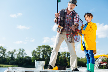 Man standing near grandson feeling happy after catching fish