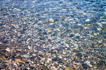Sea stones in sea water. Pebbles under water. The view from the top. Nautical background. Clean sea water. Transparent sea.