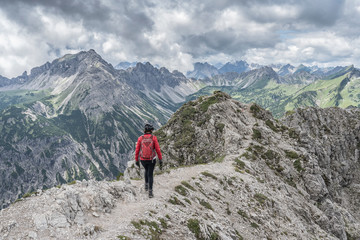 Fototapeta na wymiar nice and active senior woman approaching the summit of Litnis Schrofen during a bike and hike adventure in the Tannheim Valley, Tirol Austria