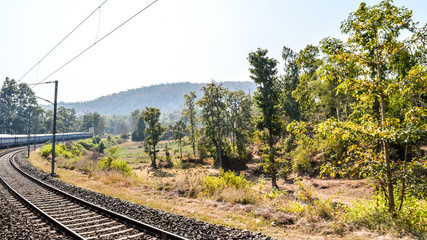 Obraz premium Train Journey In India on a mesmerizing railway tracks in Konkan Railway. Scenic train running in dense forests sides of Western Ghats in sharp bends with a lush green views and beautiful scenery.