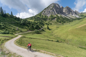 Fototapeta na wymiar nice and active senior woman, riding her e-mountain bike in the Tannheim valley on the trail up to Litnis Schrofen , Tirol, Austria, 