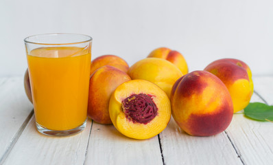 Delicious and juicy peach (nectarina) with glass of juice on white wooden table