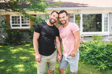 A Portrait of a happy gay couple outdoors in front of a new buy