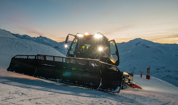 Dameuse sur une piste de ski au couch&eacute; de soleil