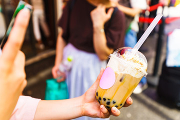 Young girl take a photo of trendy drink ( named Tapioca milk tea )