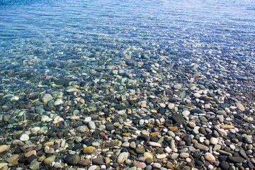 Sea stones in sea water. Pebbles under water. The view from the top. Nautical background. Clean sea water. Transparent sea.