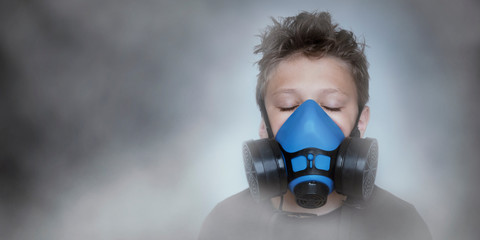 Young boy wearing gasmask, respirator portrait. Effects of worldwide air pollution, industrial...