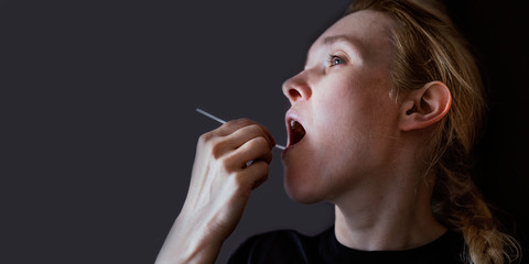 Woman doing DNA test with cotton swab at home. Test for home use. Background with copyspace