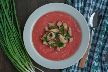 Traditional spanish cold gazpacho soup with mussels. Wooden background.